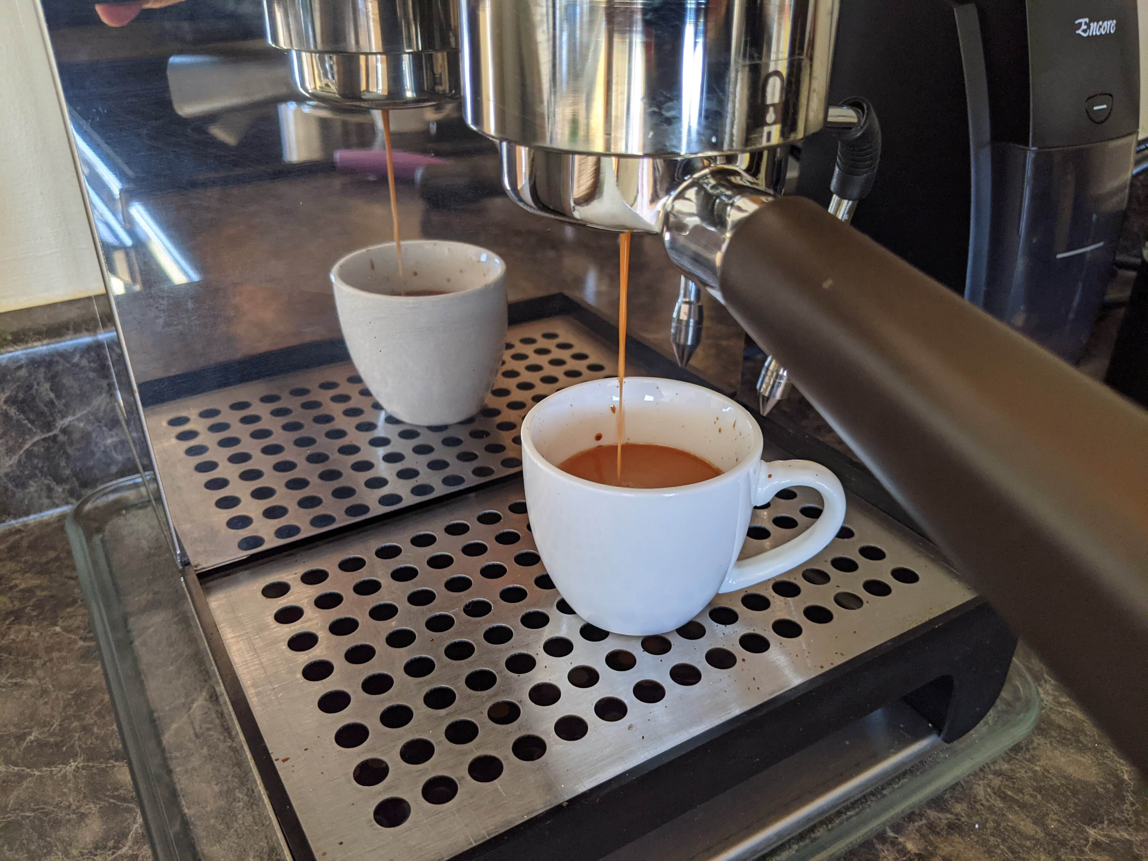 A double-spouted espresso shot pouring into a white cup on an espresso machine